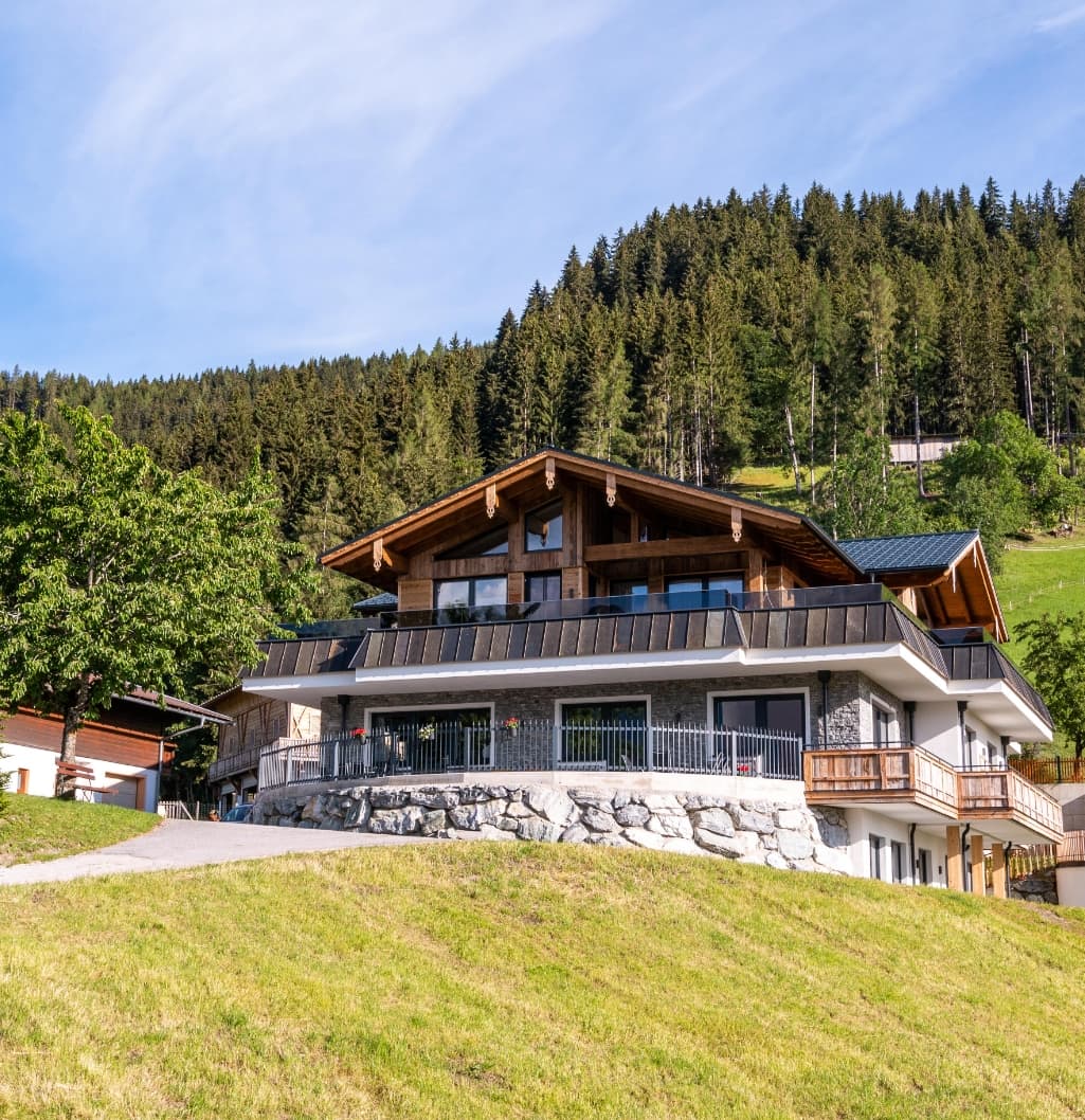 Bucheggerhof im Sommer umgeben von grünen Wiesen und Wald
