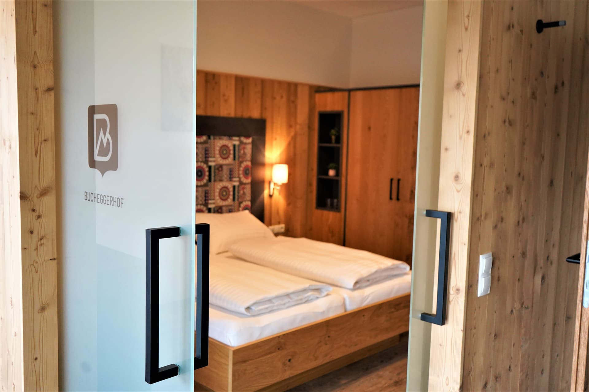 Blick durch die Glastür in ein gemütliches Schlafzimmer