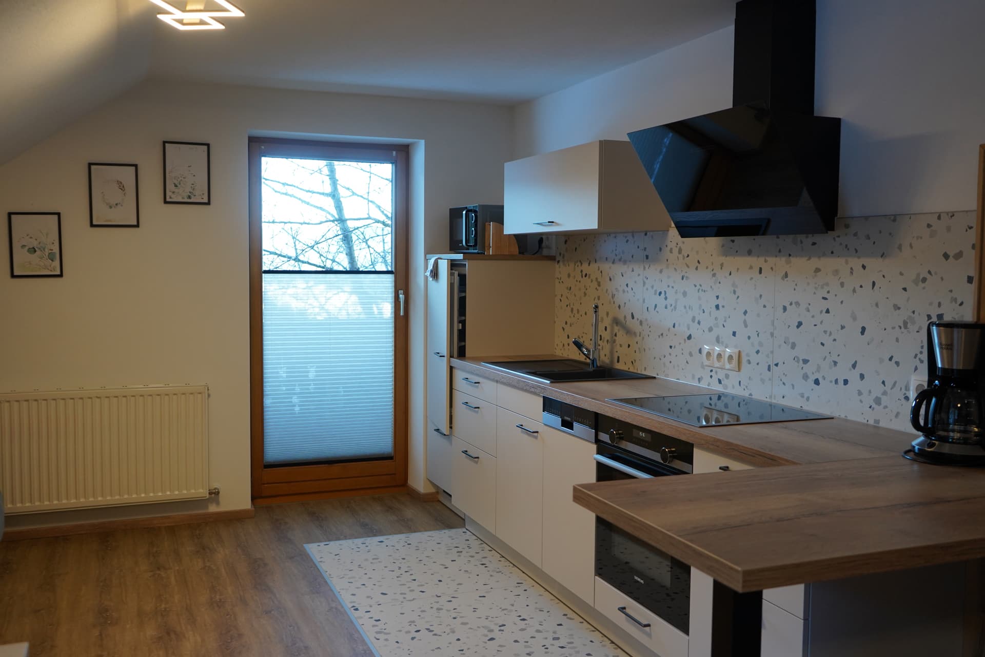 Moderne Küche im Apartment mit Kochfeld und Dunstabzug