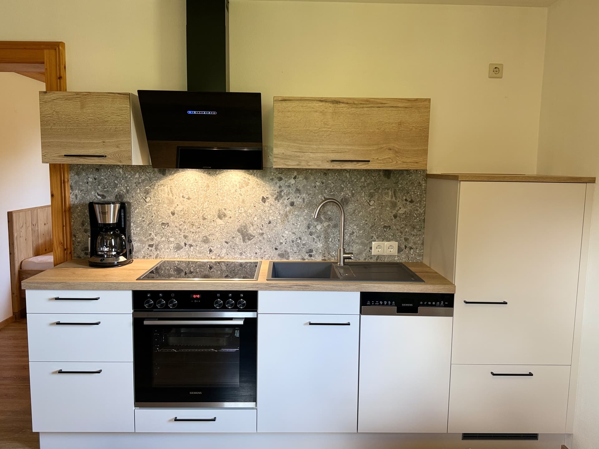 Moderne Küche mit Herd, Backofen und Kaffeemaschine im Apartment