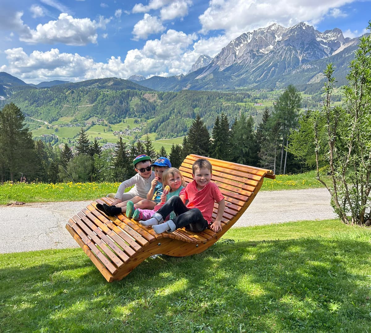 Familie beim Entspannen auf einer Panoramabank mit Bergblick