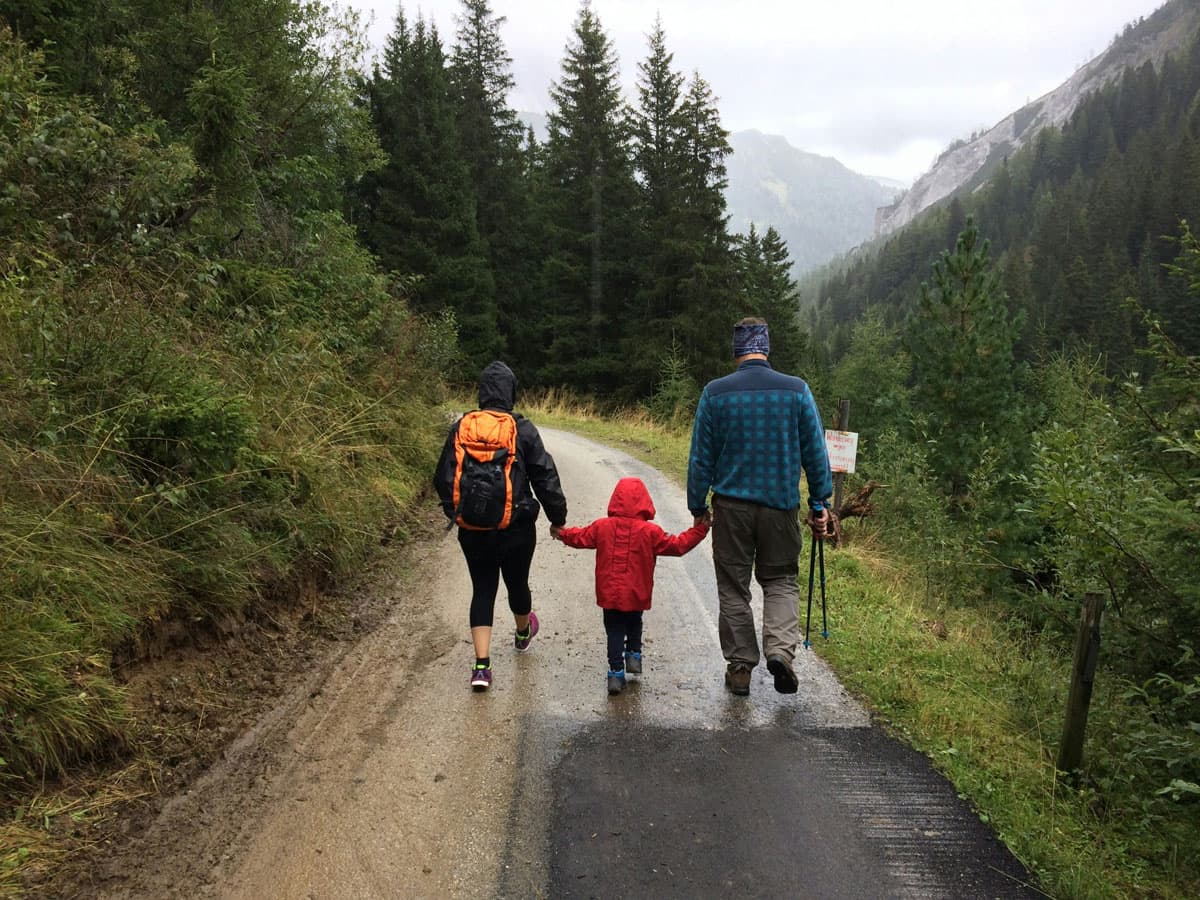 Familie beim Wandern auf einem Waldweg in den Bergen