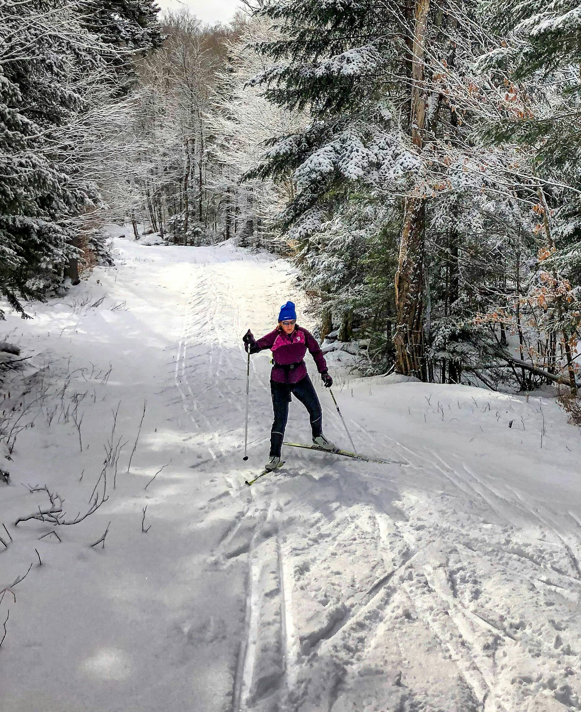 Langläuferin auf einer verschneiten Loipe im Winterwald
