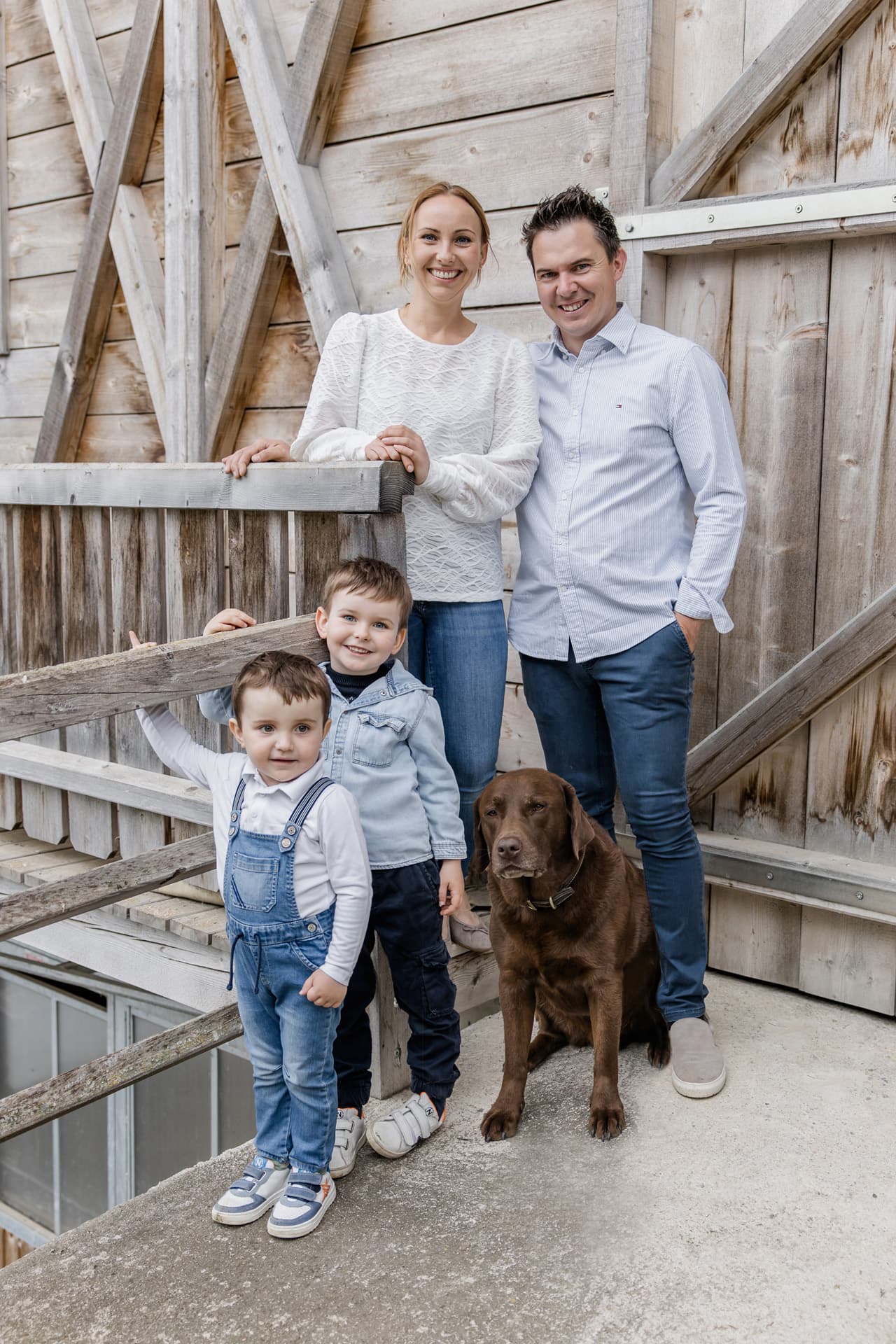Gastgeberfamilie des Bucheggerhofs mit Hund vor einer Holzhütte